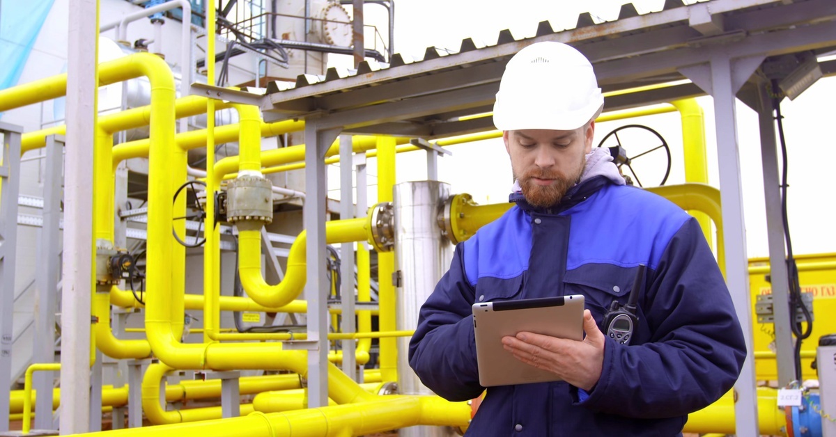 A Complete Guide to 5 Types of Photoionization Detectors An inspector surrounded by yellow gas pipes in an industrial environment. The inspector is holding a small tablet.