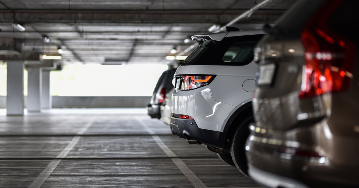 A long line of clean, modern cars waiting in parking spots inside a parking garage during the daytime.