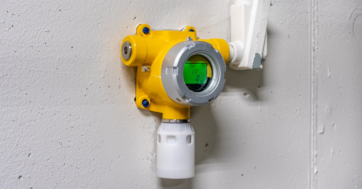A yellow, wall-mounted industrial gas detection device in an industrial wastewater treatment facility.